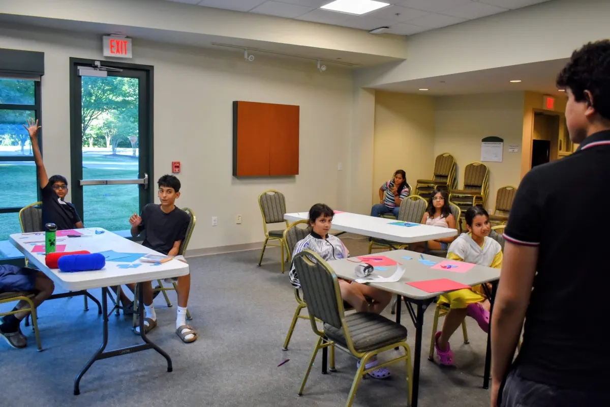 A packed community room of families and students applauding at a FutureVitals symposium in Richmond, research posters standing in the background