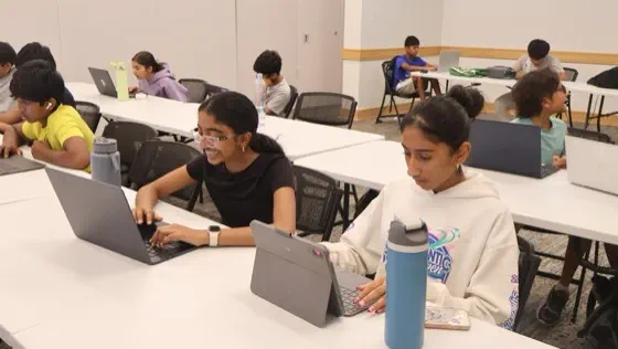 Students seated at laptops in a workshop classroom