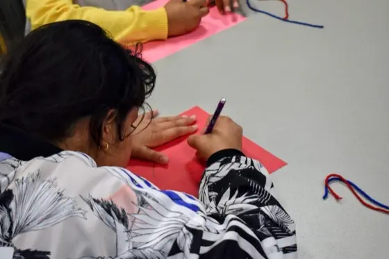 A close-up of a student's hands cutting colored paper for a craft activity
