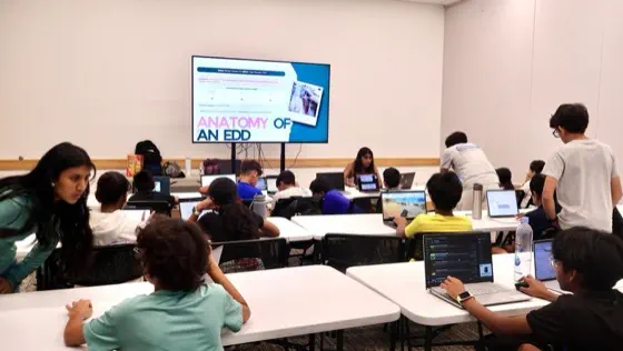 A workshop room of students on laptops, a slide reading 'Anatomy of an EDD' on the screen