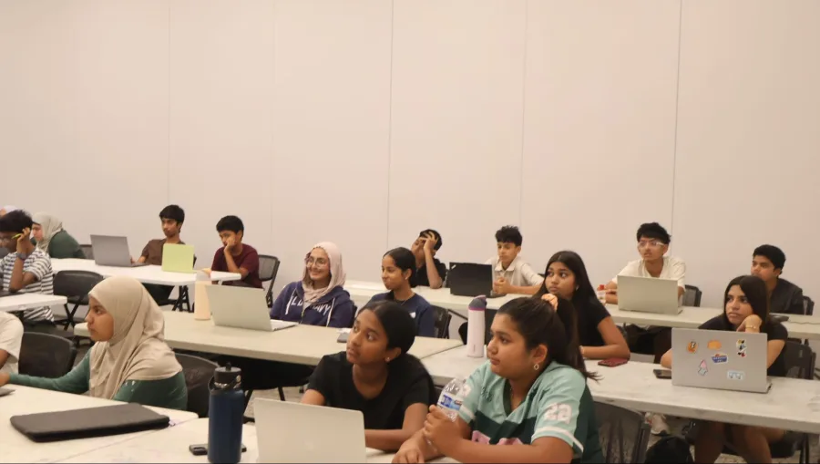 Students seated at laptops listening to a presentation