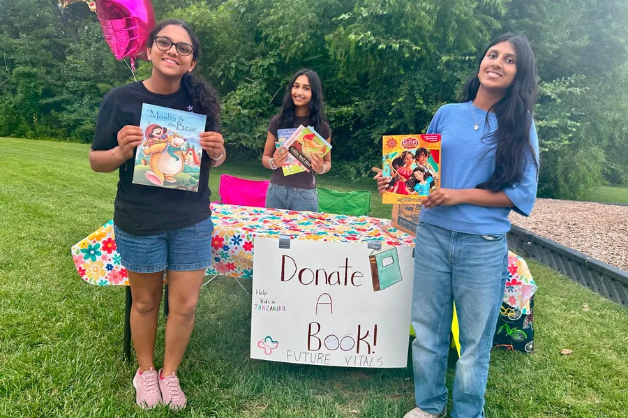 Students holding donated books behind the Donate a Book table