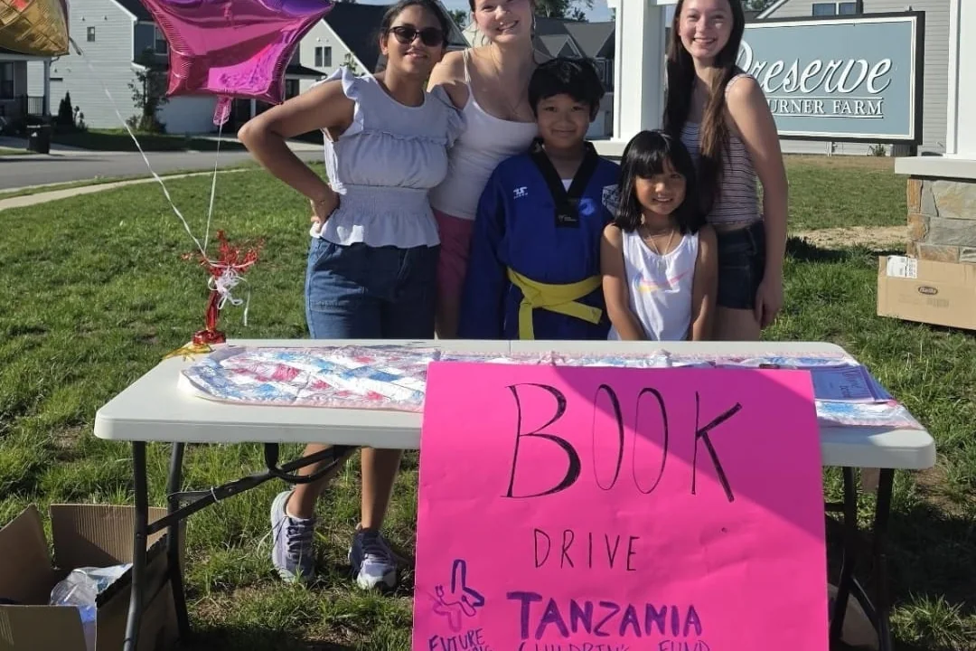 The book drive team behind the collection table, with the Tanzanian Children's Fund sign