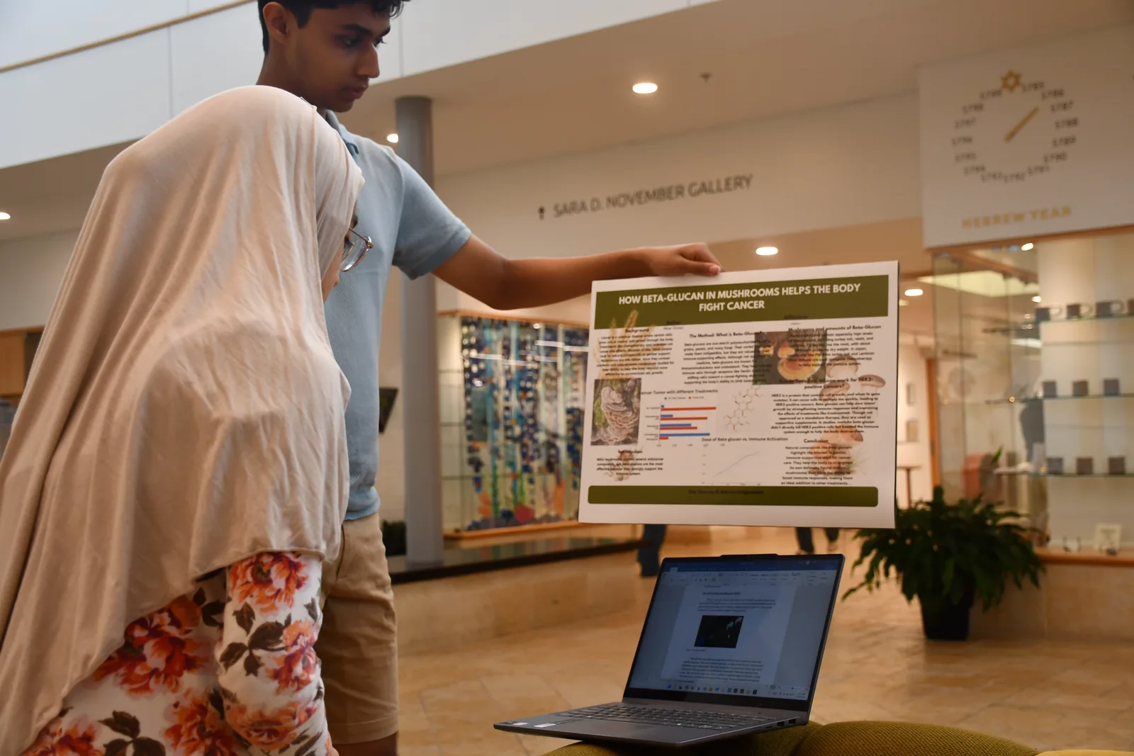 A FutureVitals student presenting a cancer research poster on beta-glucan in mushrooms while a mentor looks on