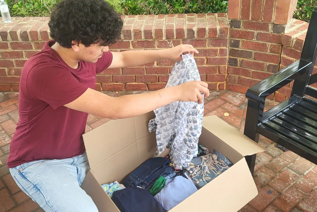 A volunteer packing sorted clothing into a donation box