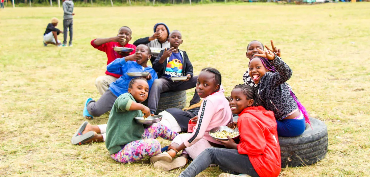 Students in Kenya sharing a meal together on a grass field