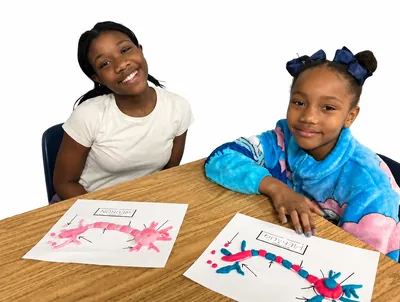 Two students smiling beside their neuron drawings