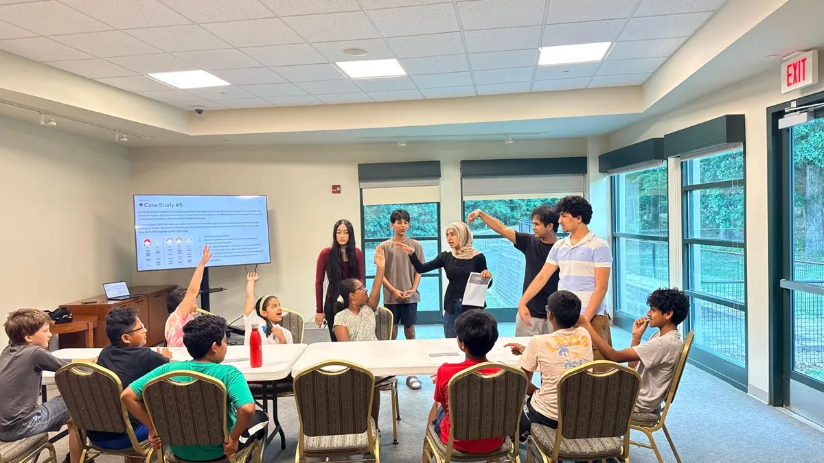 Students holding up their worksheets at a 4-H community science workshop
